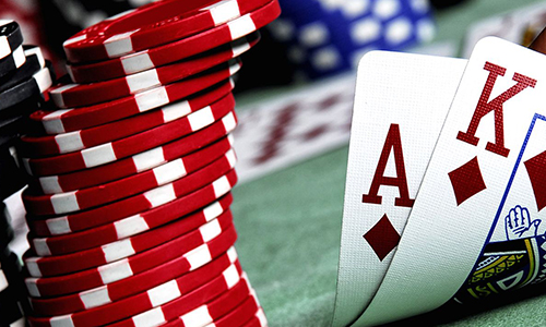 Macro fotografía de fichas de apuesta y naipes franceses en primer plano, con un fondo difuso de una mesa de casino.